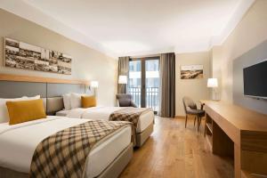 a hotel room with two beds and a flat screen tv at Ramada Hotel & Suites by Wyndham Adana in Adana +103 photos