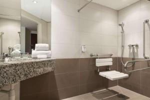 
a bathroom with a toilet, sink and mirror at Hotel Ramada Graz in Premstätten
