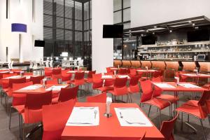 un restaurant avec des tables et des chaises rouges et un bar dans l'établissement Ramada Encore by Wyndham San Luis Potosi, à San Luis Potosí