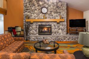 a living room with a stone wall with a fireplace at Ramada by Wyndham Platte City KCI Airport in Platte City