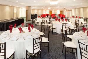 a banquet hall with white tables and chairs with red roses at Ramada Plaza by Wyndham Chicago North Shore in Wheeling