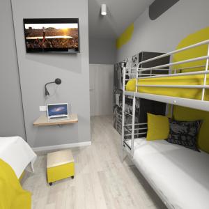 a room with bunk beds with a tv on a wall at La Guitarra Hostel Poznań in Poznań