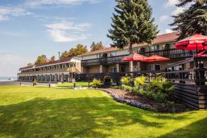 a resort building with red umbrellas on a lawn at Ramada by Wyndham Jacksons Point in Georgina