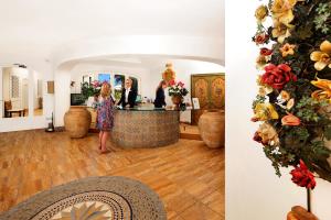 a woman standing at a counter in a room with flowers at Le Calette Bay in Cefalù