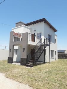 a white house with a staircase in front of it at La soleada in San Clemente del Tuyú