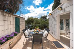 un patio con una mesa con sillas y flores en Dream Estate, en Dubrovnik