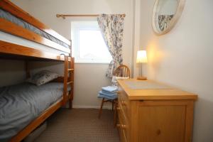 ein Schlafzimmer mit Etagenbett und Schreibtisch in der Unterkunft Beadnell Cottage in Beadnell