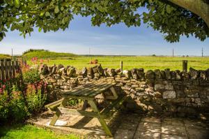 ein hölzerner Picknicktisch neben einer Steinmauer in der Unterkunft Beadnell Cottage in Beadnell