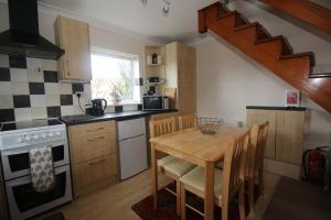 eine Küche mit einem Holztisch und einer Holztreppe in der Unterkunft Beadnell Cottage in Beadnell