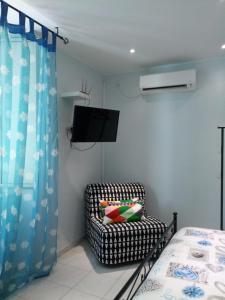 ein Schlafzimmer mit einem Bett, einem Stuhl und einem TV in der Unterkunft San Nicola Apartment Blu in Neapel