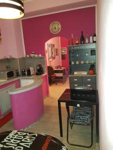 a kitchen with pink walls and a table and a clock at B&B Fontevecchia in Castelsardo