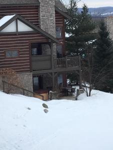 a house with a deck in the snow at Boyne Mountain Creekside Condo in Boyne Falls