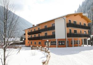 a large building in the snow with a fence at Hotel Hubertus in Mallnitz