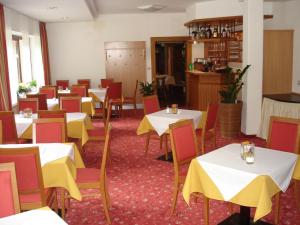 una sala da pranzo con tavoli bianchi e sedie gialle di Hotel Hubertus a Mallnitz