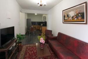 een woonkamer met een rode bank en een televisie bij Lobos Rustic House II in Câmara de Lobos