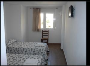 a small room with two beds and a window at Habitacions Casa Roberto in Ontinyent