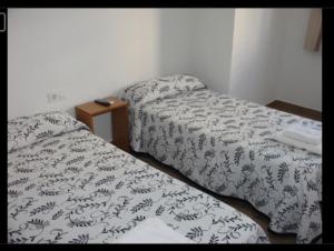 a room with two beds and a table with a bedspread at Habitacions Casa Roberto in Ontinyent