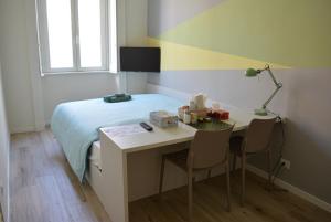 een kamer met een bed en een bureau met een bed en een tafel met stoelen bij Aria di Casa - Navigli Darsena in Milaan