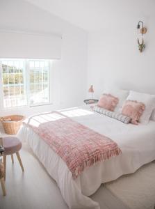 a white bedroom with a large bed with pink pillows at Casa 2Mariposas in Mijas
