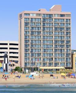 a large building on the beach with people on the beach at Four Sails Resort in Virginia Beach