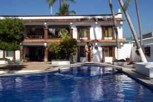 uma piscina em frente a uma casa com uma estátua em frente a ela em Hotel Posada Pablo de Tarso em San Patricio - Melaque