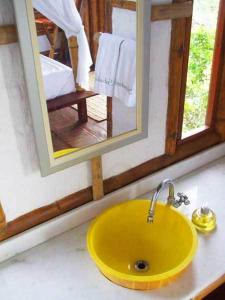 lavabo amarillo en el baño con espejo en Pousada Sabambugi, en Baía Formosa