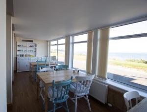 a dining room with a table and chairs and windows at Caledonian House in Portmahomack