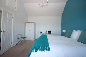 a bedroom with a large white bed and a chair at Caledonian House in Portmahomack