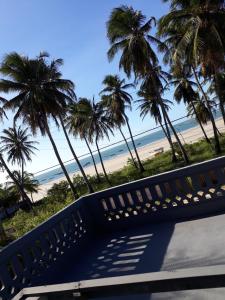 una panchina di fronte a una spiaggia con palme di Pousada Aconchego a Mundaú
