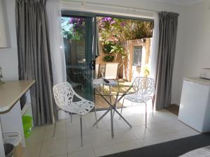 cocina con mesa de cristal y sillas en Beachport Bed & Breakfast, en Port Macquarie