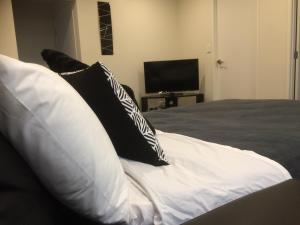 a bed with black and white pillows and a television at Crow's Nest in Picton