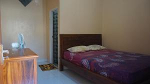 a bedroom with a bed and a wooden dresser at Arriani Homestay in Karimunjawa