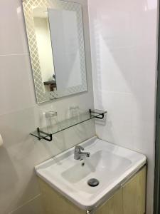 Baño blanco con lavabo y espejo en MyHome Ganggarak en Labuan