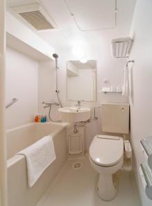 a white bathroom with a toilet and a sink at Smile Hotel Matsuyama in Matsuyama