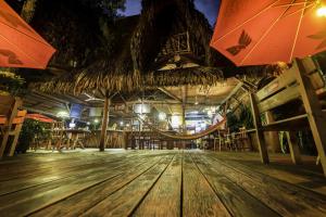 ein Restaurant mit Holzboden und 2 Sonnenschirmen in der Unterkunft Hotel Casa Perico in Rio Dulce