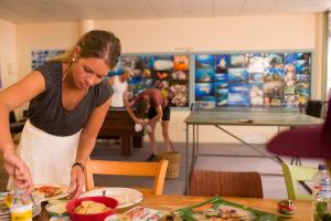 uma mulher a preparar um prato de comida numa mesa em Manta Lodge YHA & Scuba Centre em Point Lookout