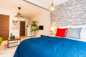 Un dormitorio con una cama azul y una pared de ladrillo en FDS En Osaka, en Osaka