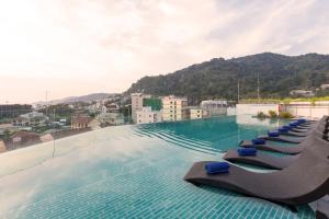 a swimming pool with lounge chairs on top of a building at Journeyhub Phuket Patong in Patong Beach