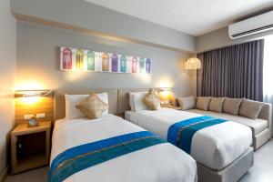 a hotel room with two beds and a couch at Journeyhub Phuket Patong in Patong Beach