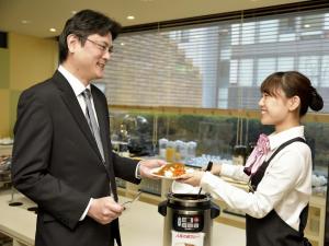 un hombre entregando a una mujer un plato de comida en Hotel Fukuoka Garden Palace, en Fukuoka