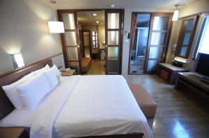 a bedroom with a large white bed and a television at Kindness Hotel - Hanshen in Kaohsiung