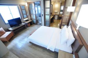 a hotel room with a bed and a television at Kindness Hotel - Hanshen in Kaohsiung