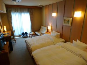 a hotel room with two beds and a chair at Kasuga Hotel in Nara