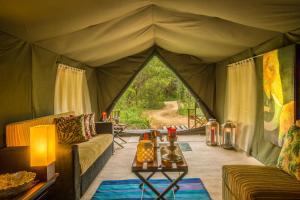 Mahoora - Udawalawe by Eco Team في اوداوالاوي: غرفة معيشة في خيمة مع أريكة وطاولة