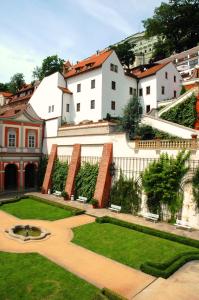 un gran edificio blanco con un jardín delante de él en Golden Well, en Praga
