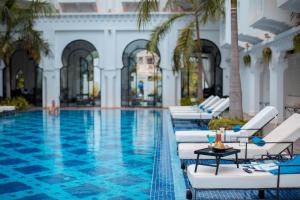 a pool with chaise lounge chairs and palm trees at Sarai Resort & Spa and The Wander in Siem Reap
