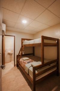 a bedroom with two bunk beds and a bathroom at Airport Inn Managua in Managua