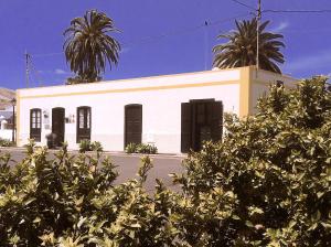 a white building with two palm trees in front of it at La Finca Uga in Uga