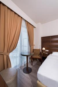 1 dormitorio con cama, mesa y ventana en Agrinio Imperial Hotel, en Agrinio