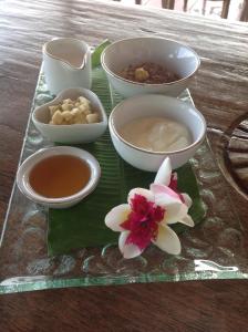 una bandeja con tazones y flores en una mesa en The Raja Singha Boutique Resort Bali, en Lovina